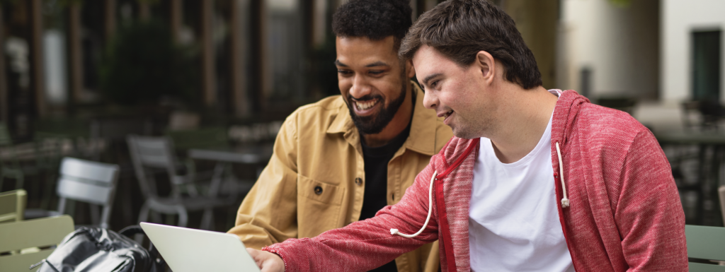 PA Employer points to things of interest on a laptop screen while his Personal Assistant looks on.