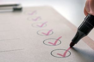 A pen marks red ticks on a checklist