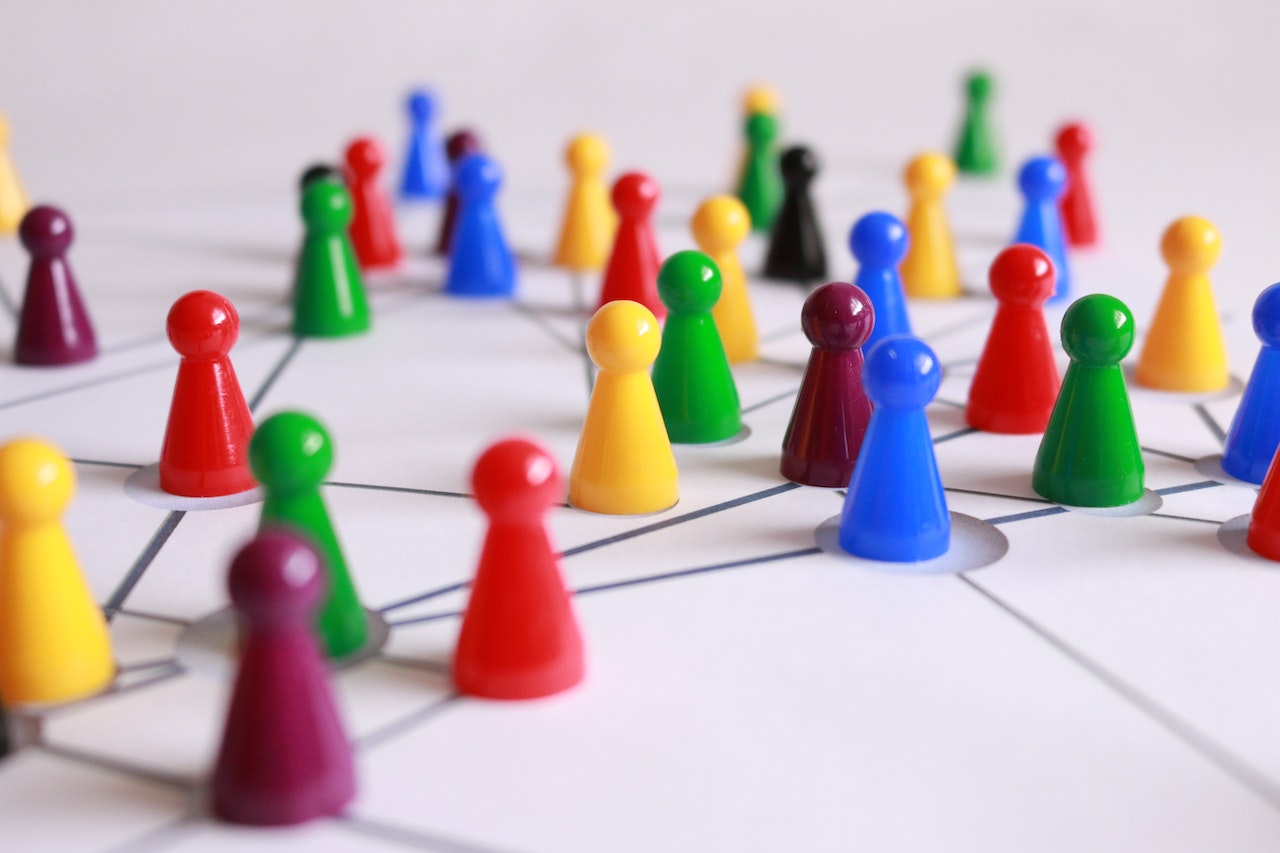 Small abstract plastic figures arranged on an image of a network showing the connections between them