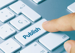 computer keyboard with someone's finger hovering over a button that says publish