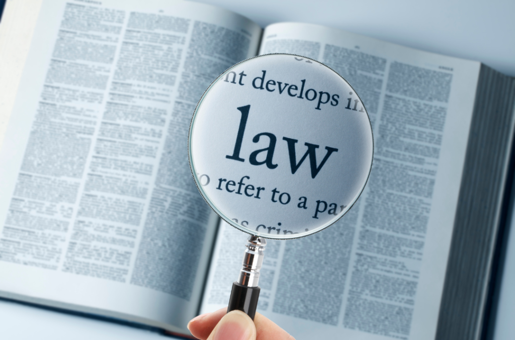 A magnifying glass hovering over a book, focusing on the word 'law'