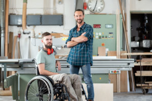 A PA Employer is in his workshop, with his PA standing beside him